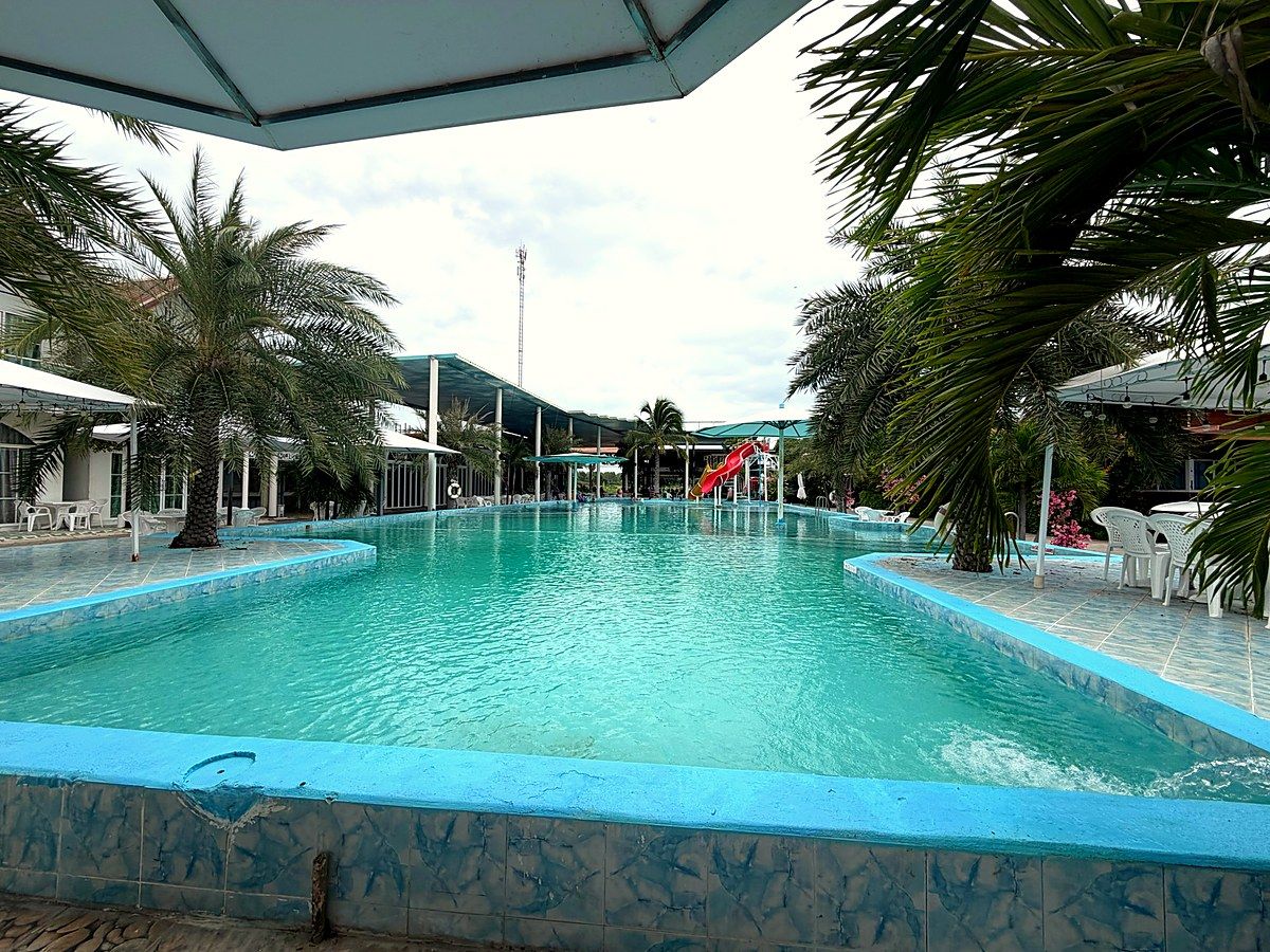 Großzügiger Pool des Resorts, gesäumt von Palmen und überdachten Sitzplätzen