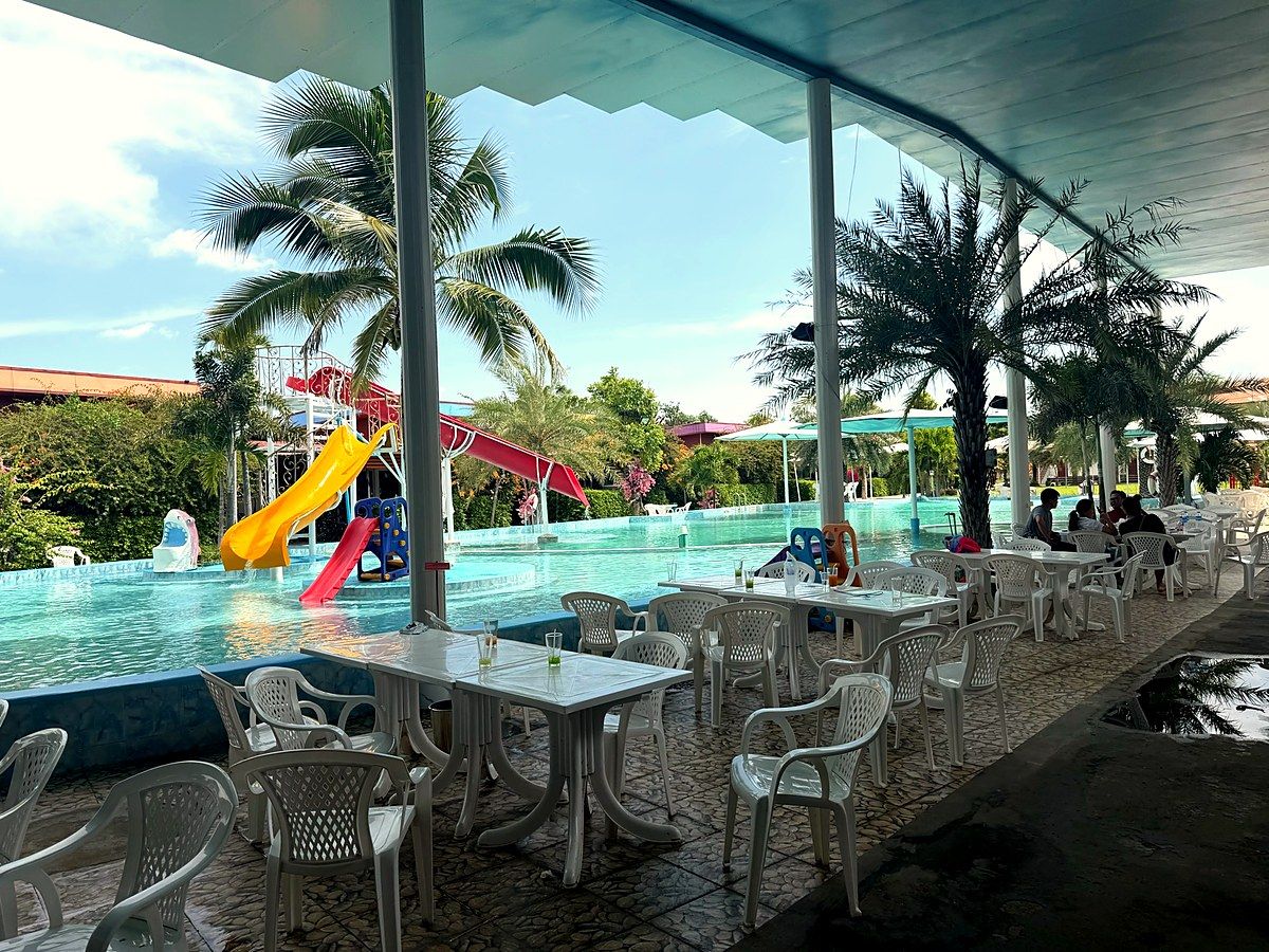 Überdachte Terrasse mit Tischen direkt am Pool