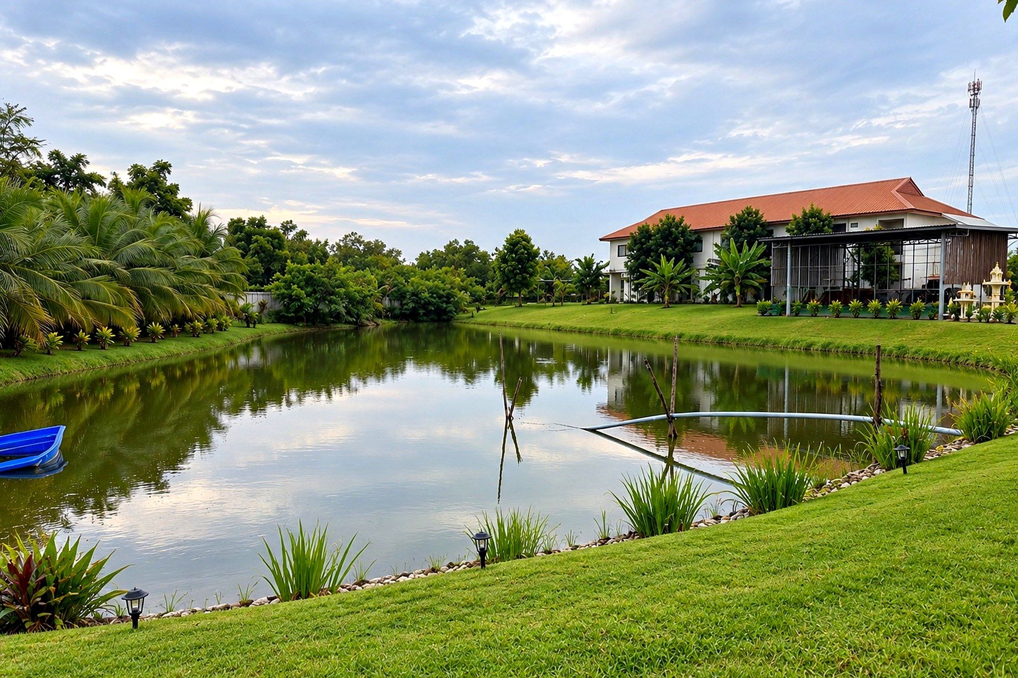 Blick über den ruhigen Teich des Resorts auf das Haupthaus, umgeben von Rasen und tropischem Grün